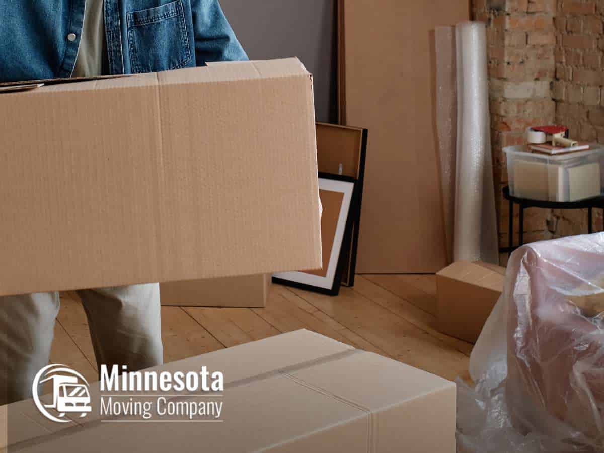 Person packing boxes in preparation for a long-distance move, Minnesota Moving Company logo visible